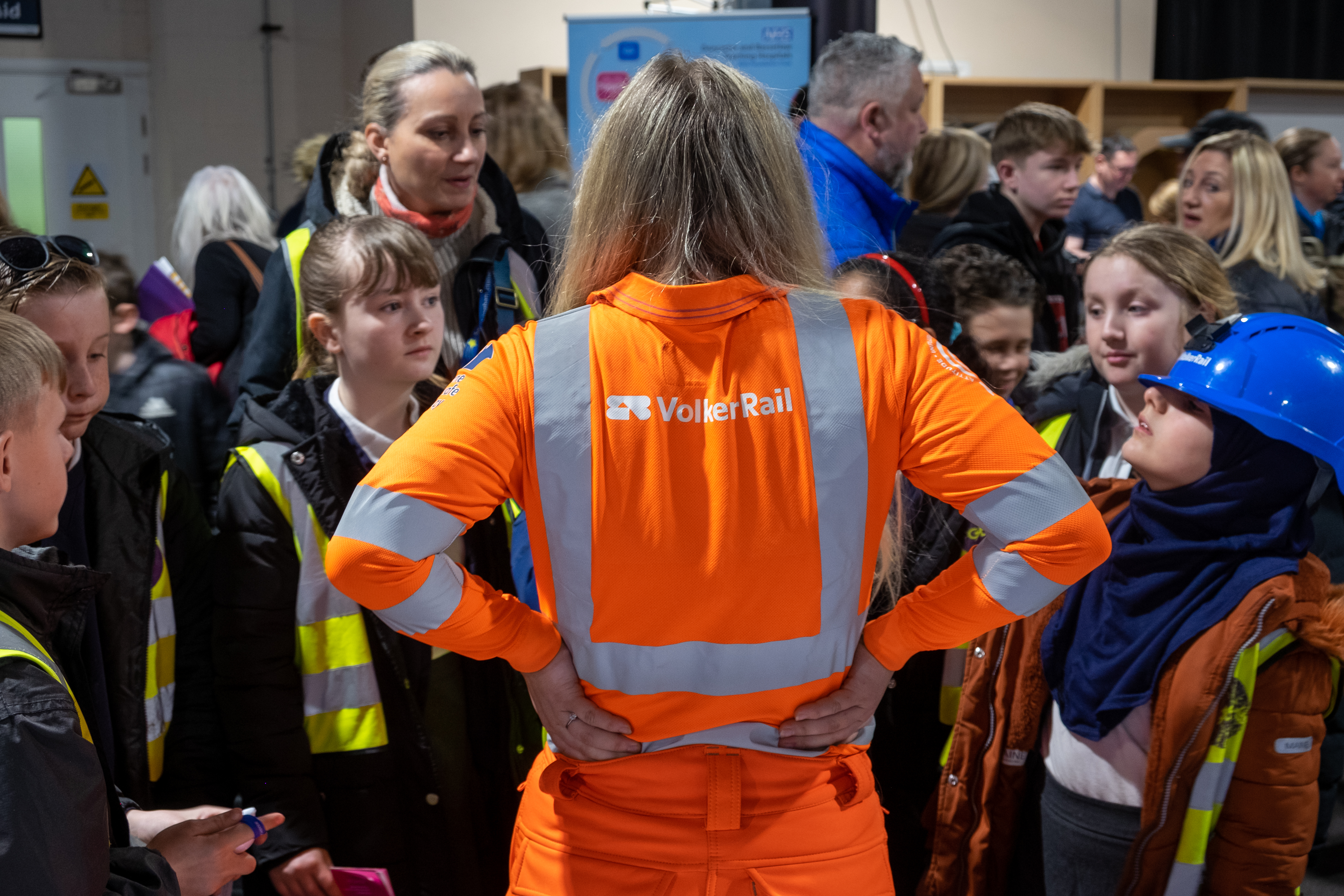 women wearing a VolkerRail PPE top with children surrounding her