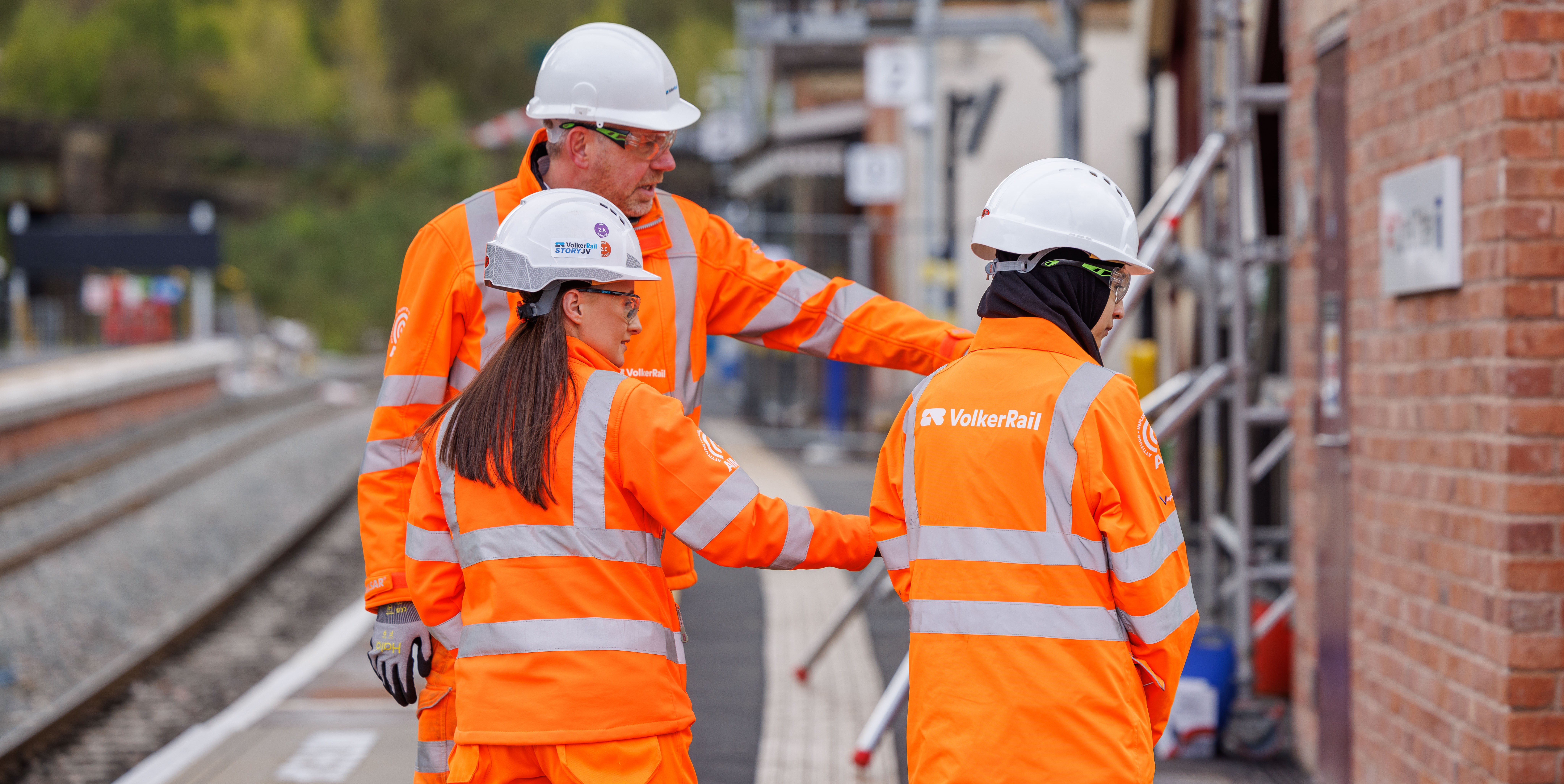 A group of people in orange PPE on a train station platform