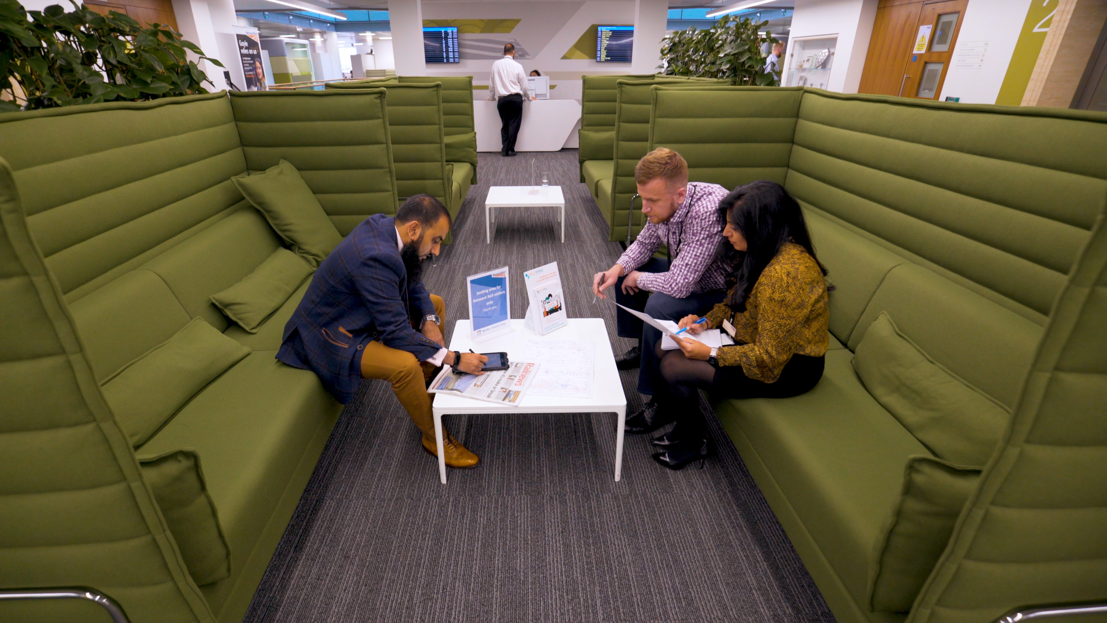 three people having a meeting on big green sofas